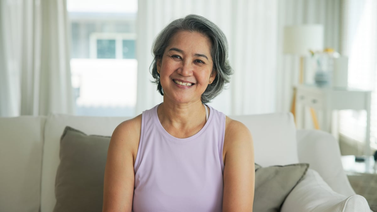 Mature woman with natural healthy skin sitting relaxed at home, smiling gently