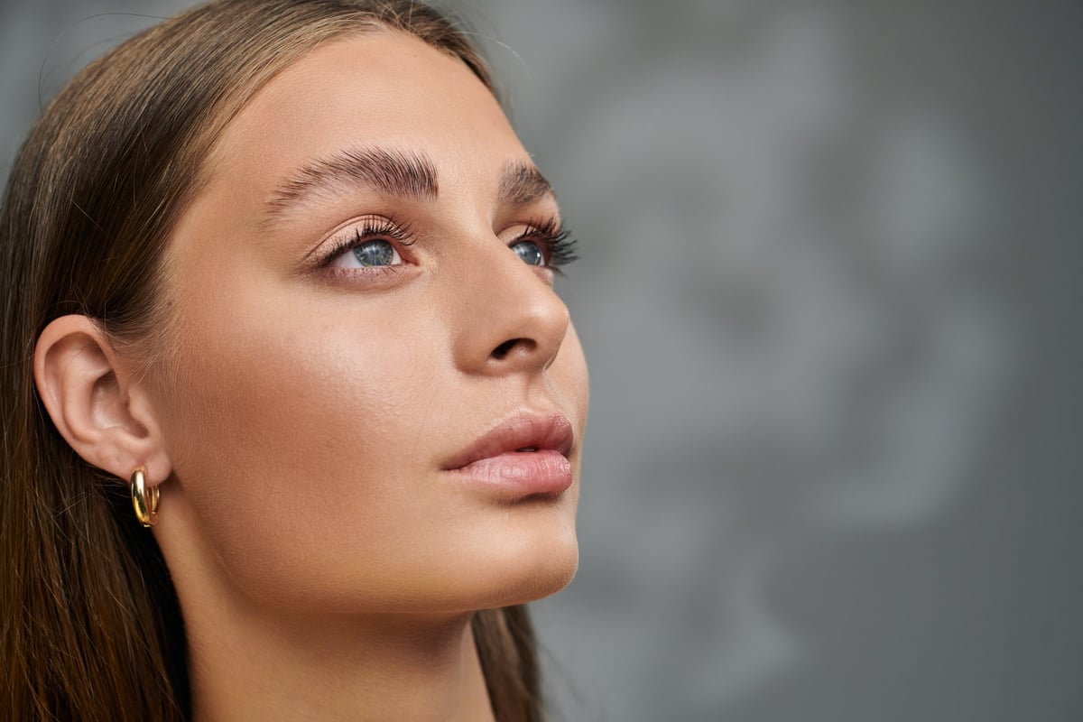 Woman with tan skin and natural makeup in a relaxed studio setting, representing skin quality